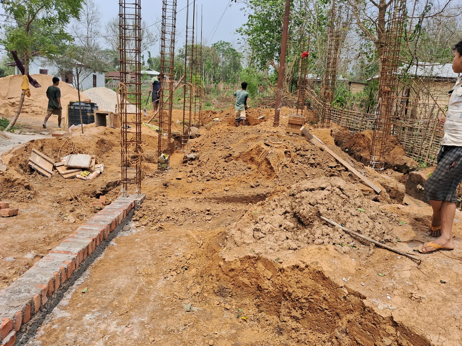 Overview of hostel construction site with workers and materials
