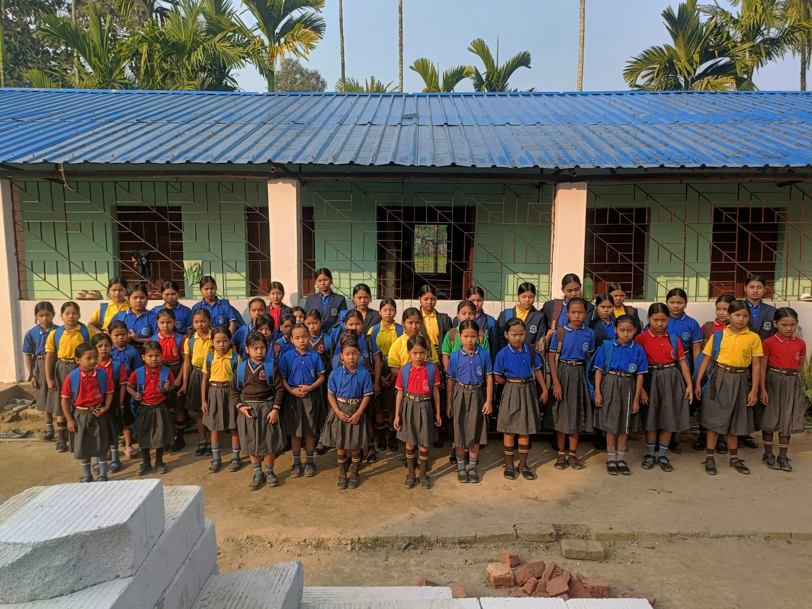 Tribal school students in uniform standing in front of their school