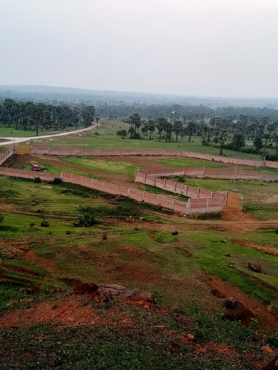 Boundary wall construction at Labri project site with winding road and hills